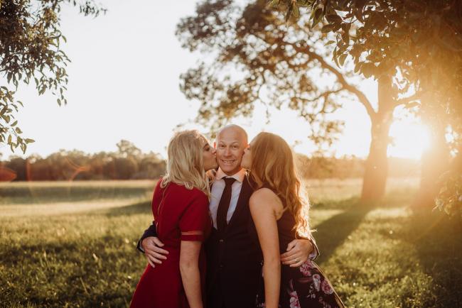 20180909-DSC_5554 Two daughters kiss their fathers cheeks during golden hour family photography Perth session at Perry's Paddock