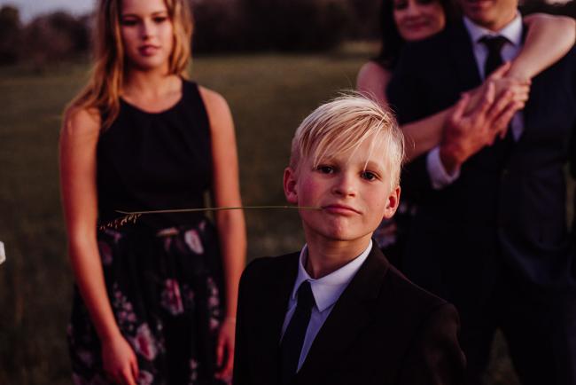 20180909-DSC_6378 Boy looks at camera with flower in his mouth during golden hour family photography Perth session at Perry's Paddock