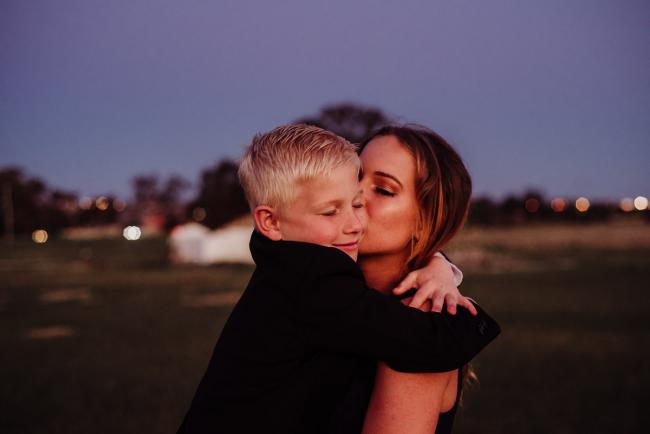 Big sister carrying and kissing her younger brother during a family photography session at Perry's Paddock, Perth