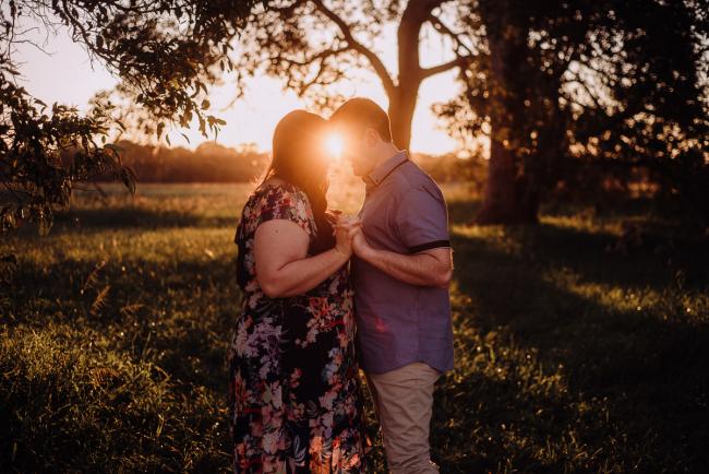 Couple standing holding hands with a sunburst between them during a couples photography session at Perry's Paddock, Perth