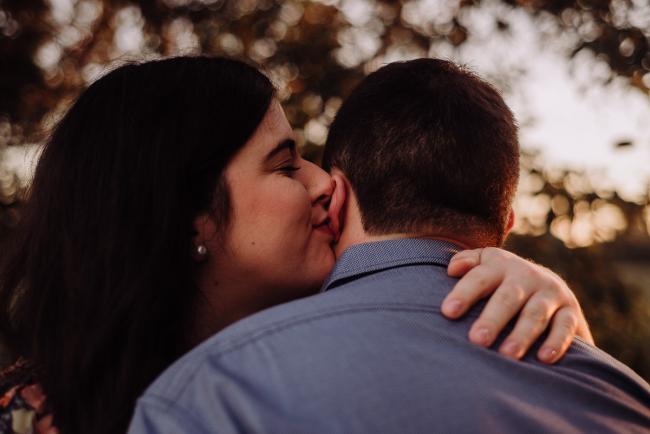 Woman kisses her partner's ear with her hand wrapped around his neck during a couples photography session at Perry's Paddock, Perth
