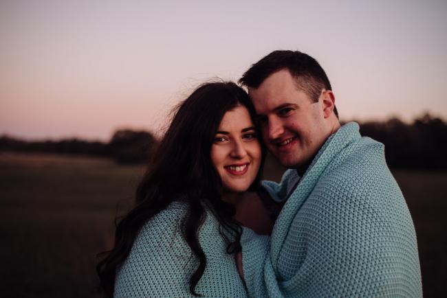 Couple smiling at the camera with a blanket around them during a couples photography session at Perry's Paddock, Perth
