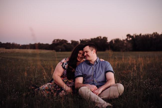 Couple sitting on the grass and leaning in towards each other during a couples photography session at Perry's Paddock, Perth
