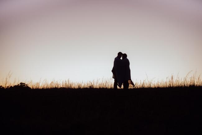 Silhouette of a couple with a blanket around them and foreheads touching during a couples photography session at Perry's Paddock, Perth