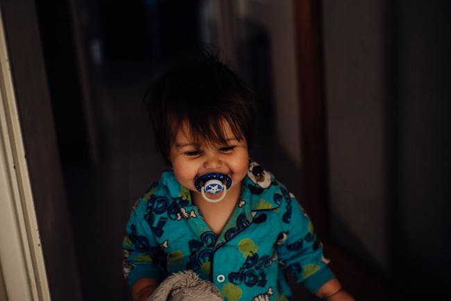 Little boy in his pyjama's and smiling with a dummy in his mouth by family photographer perth