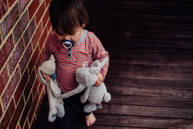 Little boy holding onto his toy bunnies outside by family photographer perth