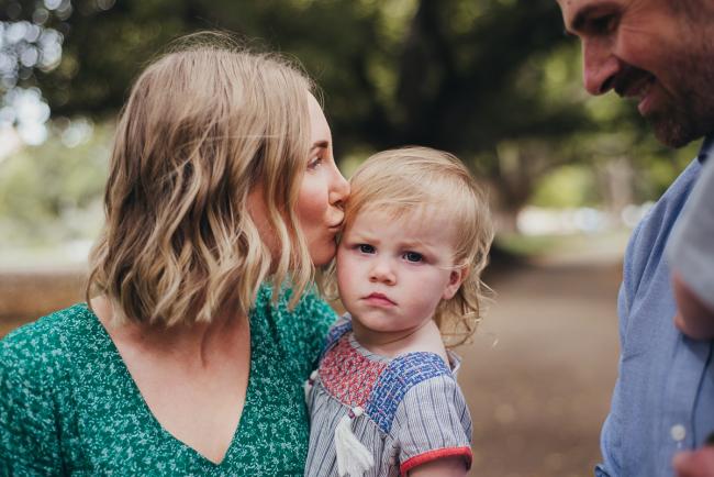 Mother kissing her daughter during a family photography session at Hyde Park in Perth