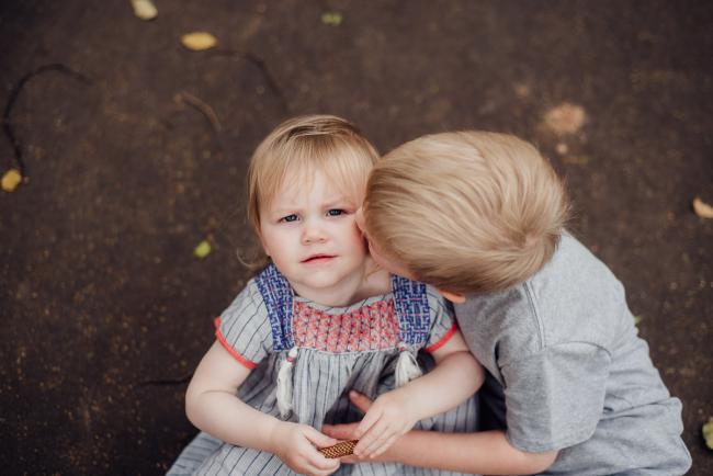 Brother kissing his sister during a family photography session at Hyde Park in Perth