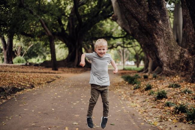 Little boy jumping during a family photography session at Hyde Park in Perth