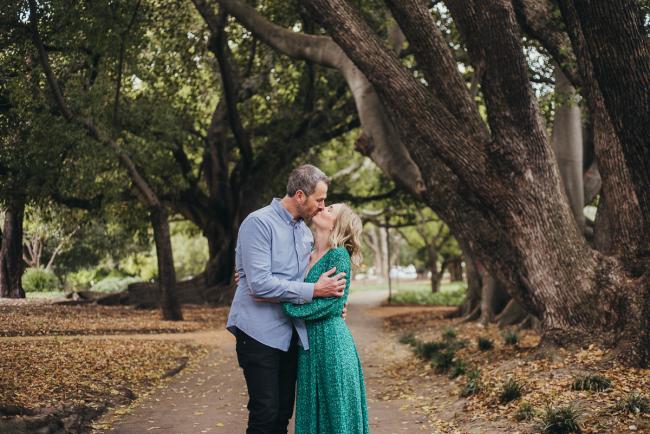 Couple kissing during a family photography session at Hyde Park in Perth
