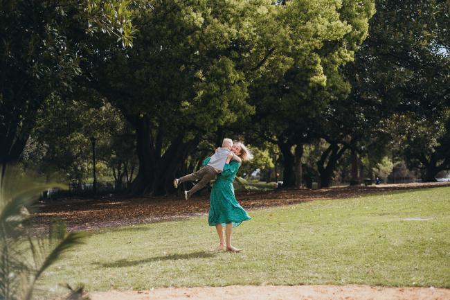 Mother spinning her son around during a family photography session at Hyde Park in Perth