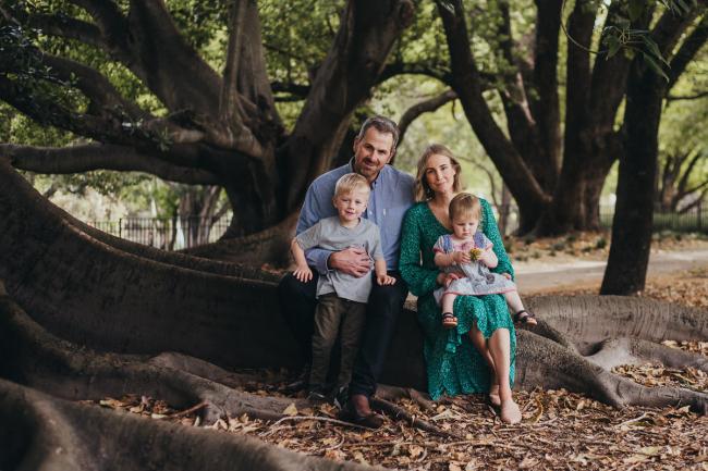 Family of 4 sitting on a tree during a family photography session at Hyde Park in Perth