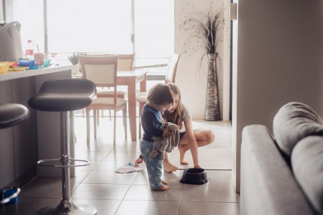 Girl picking up a dog water bowl as her little brother looks at it whilst holding his bunnies, by family photographer perth