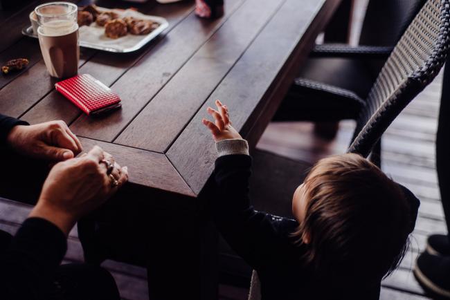Toddler reaching up to get food on an oustide table by family photographer perth
