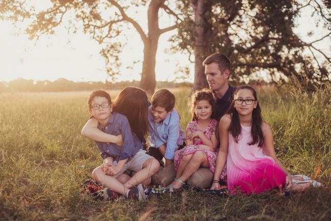 Family of 6 sitting on the grass during a golden hour family photography session at Perry's Paddock in Perth