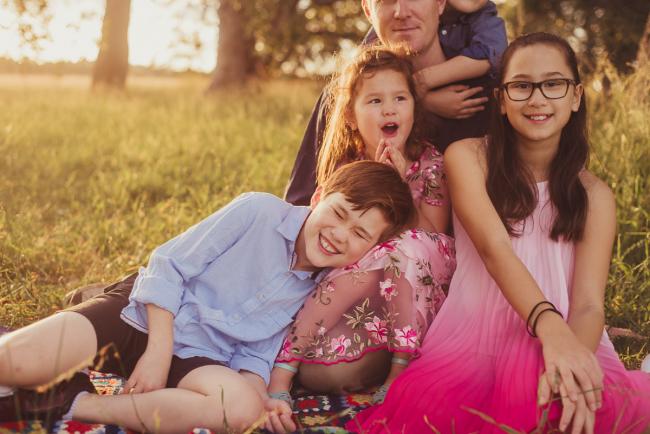 Boy leaning on his younger sister and laughing during a golden hour family photography session at Perry's Paddock in Perth