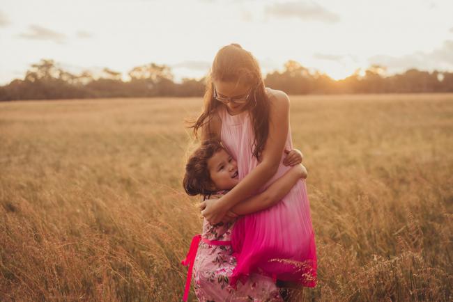Two sisters hugging during a golden hour family photography session at Perry's Paddock in Perth