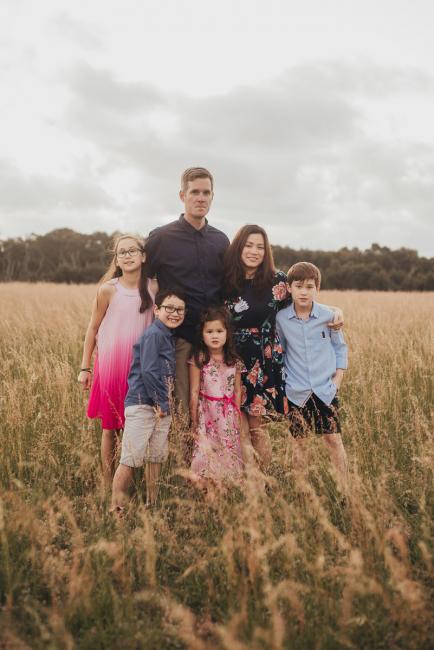 Family of 6 standing in a field during a golden hour family photography session at Perry's Paddock in Perth