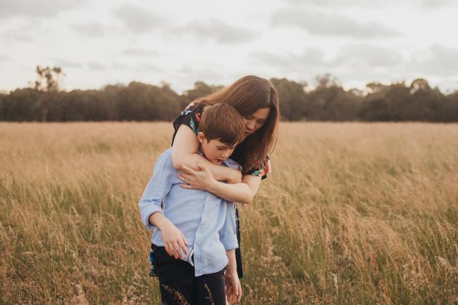 Mother hugging her son from behind during a golden hour family photography session at Perry's Paddock in Perth
