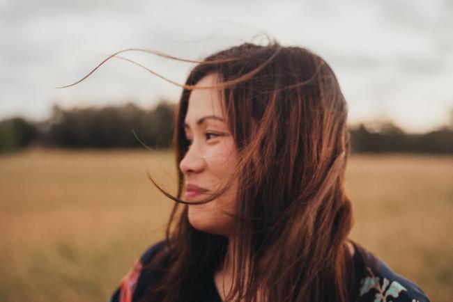Beautiful woman looking to the side as her hair blows in the wind during a golden hour family photography session at Perry's Paddock in Perth