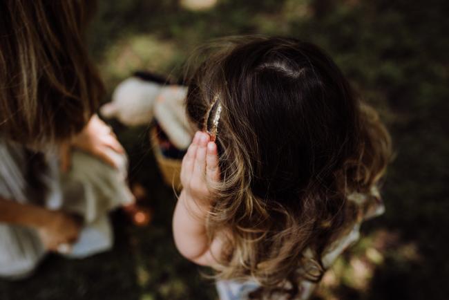 Top down image of a little girl touching her hair clip during a mini session with Perth family photographer at Hyde Park