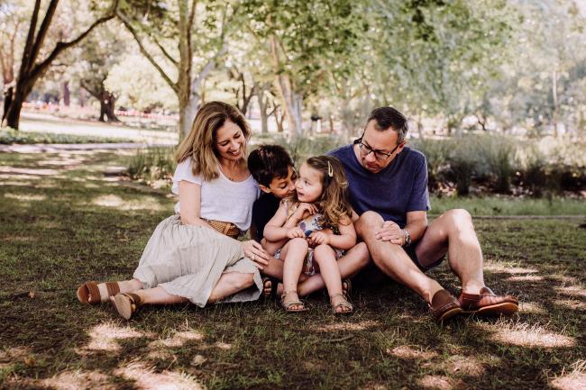 Family of 4 sitting on the grass during a mini session with Perth family photographer at Hyde Park