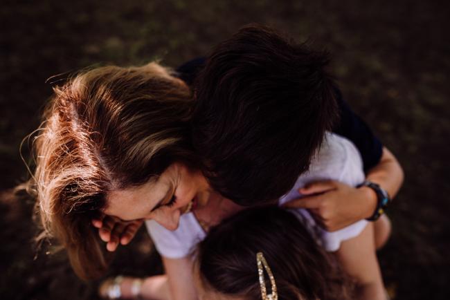 Top down shot of a mother being hugged by her son and daughter during a mini session with Perth family photographer at Hyde Park
