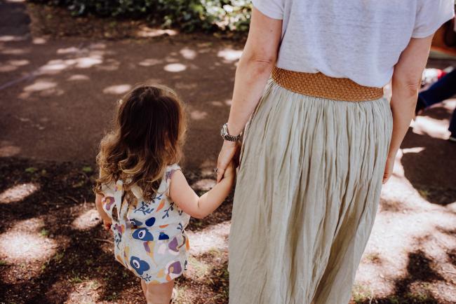 Little girl and mother holding hands and walking away during a mini session with Perth family photographer at Hyde Park