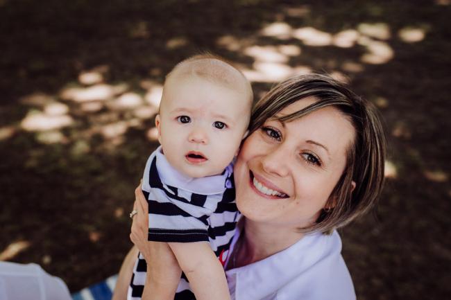 mother smiling and holding her baby son during a mini session with Perth family photographer at Hyde Park