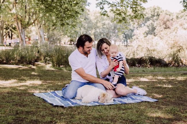mother and father sitting on a rug with their baby son and dog during a mini session with Perth family photographer at Hyde Park