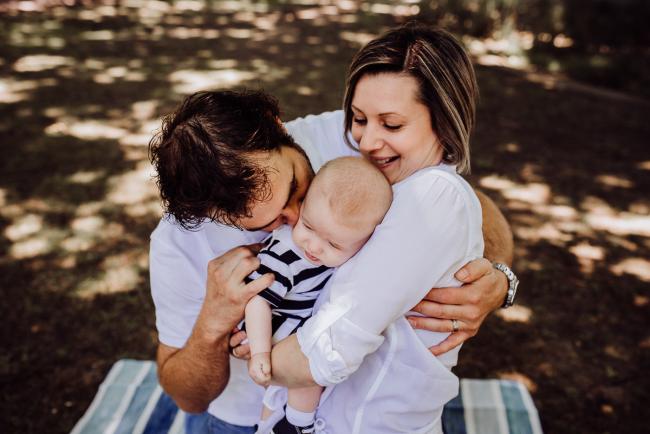 mother, father and baby son hugging during a mini session with Perth family photographer at Hyde Park