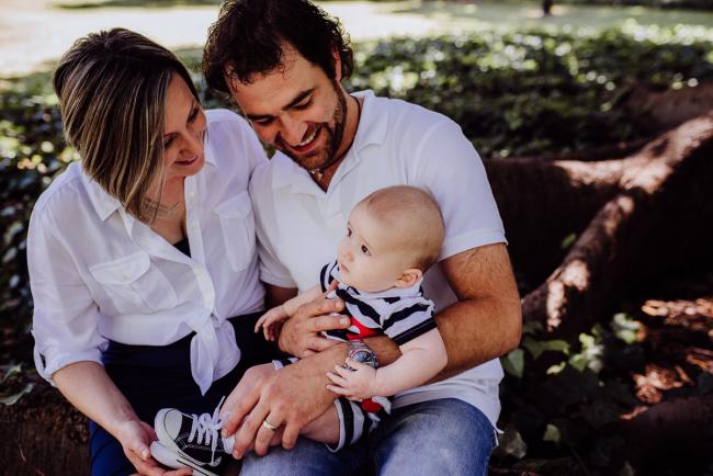 mother and father smiling down at their baby son during a mini session with Perth family photographer at Hyde Park
