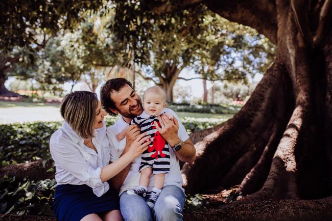 mother and father smiling at their baby son during a mini session with Perth family photographer at Hyde Park