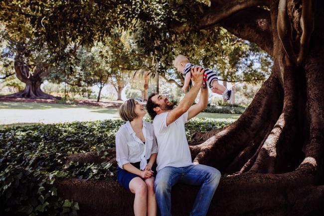 Father lifting his baby son into the air during a mini session with Perth family photographer at Hyde Park