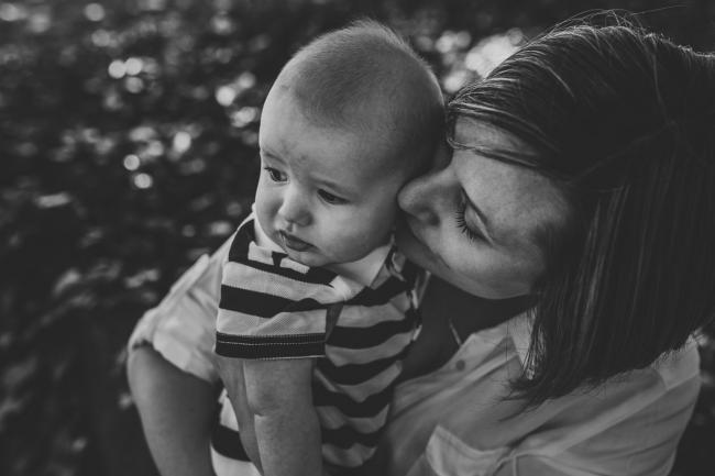 Black and white image of a mother kissing her baby son during a mini session with Perth family photographer at Hyde Park