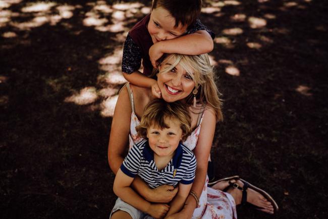 20181104-DSC_6982 mother sitting with her son on her lap and her other son sprawled over her head during a mini session with Perth family photographer at Hyde Park