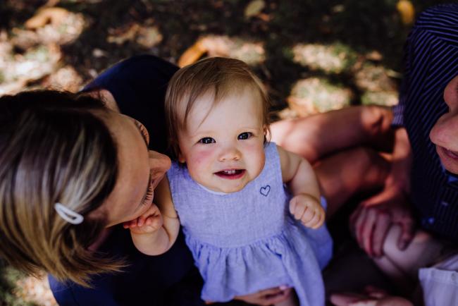 Little girl smiling up at the camera during a mini session with Perth family photographer at Hyde Park