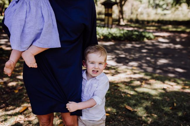 Little boy hugging his mothers leg during a mini session with Perth family photographer at Hyde Park
