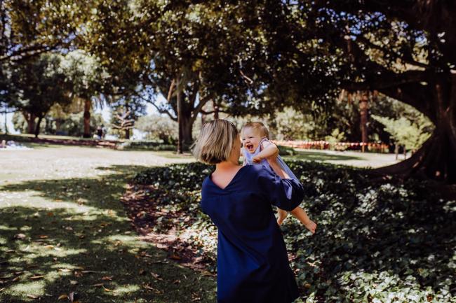 Little girl being thrown in the air by her mum during a mini session with Perth family photographer at Hyde Park