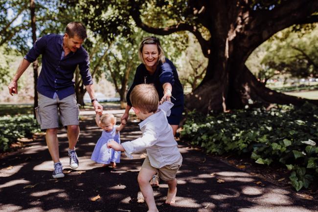 Little boy leading his family in follow the leader during a mini session with Perth family photographer at Hyde Park