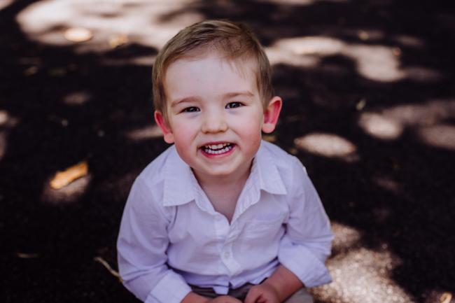 Little boy smiling at the camera during a mini session with Perth family photographer at Hyde Park
