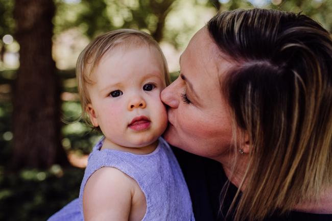 Little girl being kissed by her mum during a mini session with Perth family photographer at Hyde Park