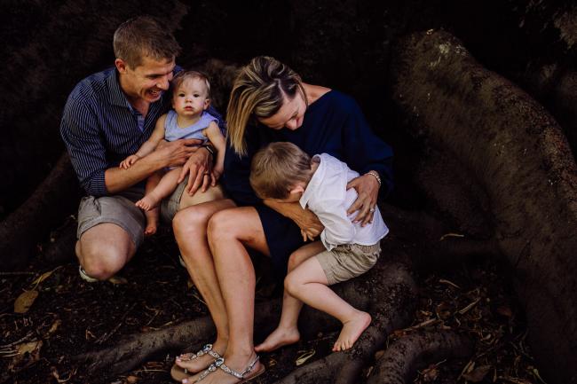 Family of 4 sitting in the bough of a tree during a mini session with Perth family photographer at Hyde Park