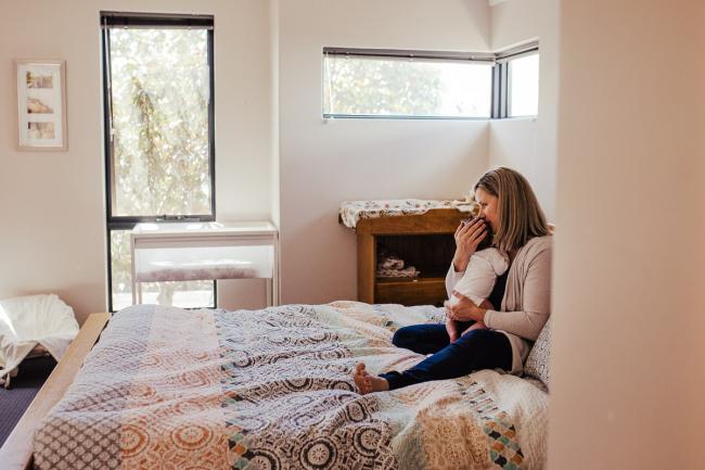 20181111-DSC_8261-2 Mum sitting on her bed holding her new baby in a lifestyle family photography session Perth