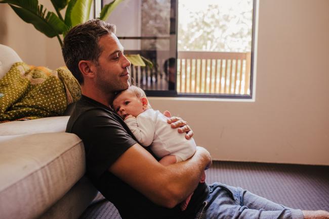20181111-DSC_8515-2 Dad sitting on the floor holding his new baby in a lifestyle family photography session Perth