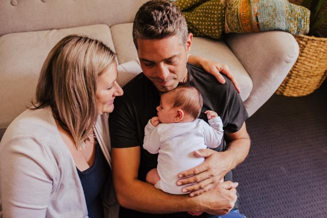 20181111-DSC_8528-1 Parents sitting on the floor holding their new baby in a lifestyle family photography session Perth