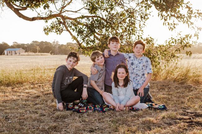 Cousins sitting on the grass during golden hour family photography session at Perry's Paddock Perth