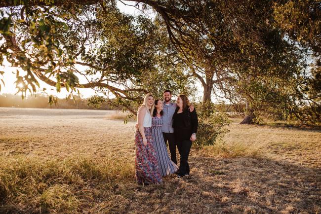 Four grown siblings standing under a tree during golden hour family photography session at Perry's Paddock Perth