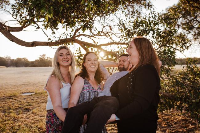 Three grown sisters carrying their grown brother during golden hour family photography session at Perry's Paddock Perth