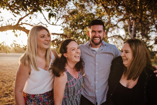 Four grown siblings laughing during golden hour family photography session at Perry's Paddock Perth